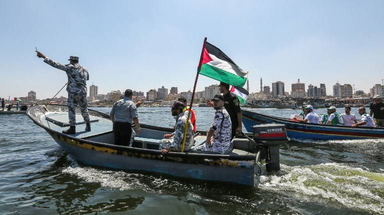 Un barco que transportaba miembros de la policía marina de Hamás escolta un barco lleno de palestinos heridos durante la violencia que perpetraron a lo largo de la valla de seguridad de Gaza para iniltrarse en Israel. (Mahmud Hams / AFP)