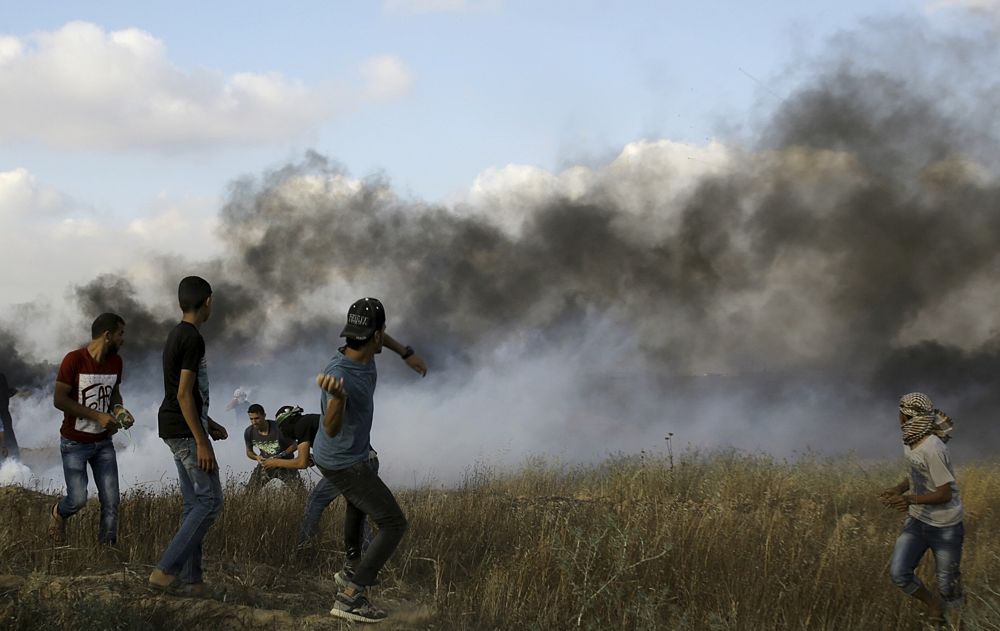 Un islamista palestino arroja piedras a las tropas israelíes después de quemar neumáticos cerca de la frontera de la Franja de Gaza con Israel, durante una manifestación islamista al este de Khan Younis, en la Franja de Gaza el 1 de junio de 2018. (AP Photo / Adel Hana)