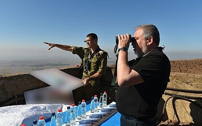 El ministro de Defensa, Avigdor Liberman, observa con prismáticos la cima de una colina que domina la frontera con Siria como Brig. El general Amit Fisher le informa sobre los acontecimientos en la zona, el 10 de julio de 2018. (Ariel Hermoni / Ministerio de Defensa)