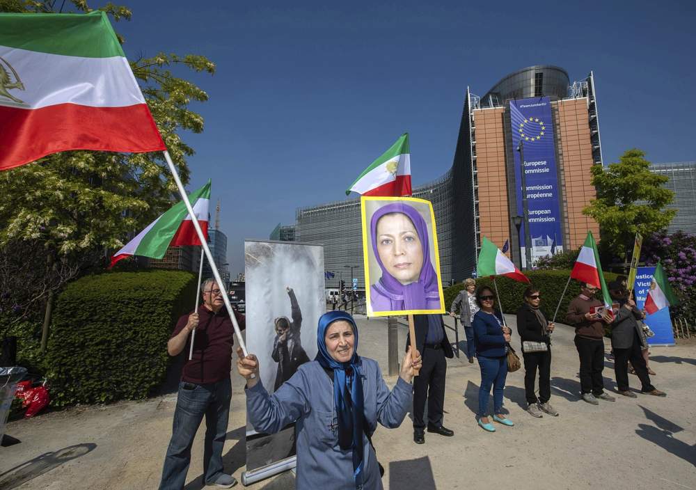 Los partidarios del Consejo Nacional de Resistencia de Irán agitan banderas y sostienen una foto de Maryam Rajavi, líder de los muyahidín del pueblo de Irán, fuera de una reunión del canciller iraní Javad Zarif y la jefa de política exterior de la Unión Europea Federica Mogherini en el edificio Europa en Bruselas el martes, 15 de mayo de 2018. (AP Photo / Olivier Matthys)