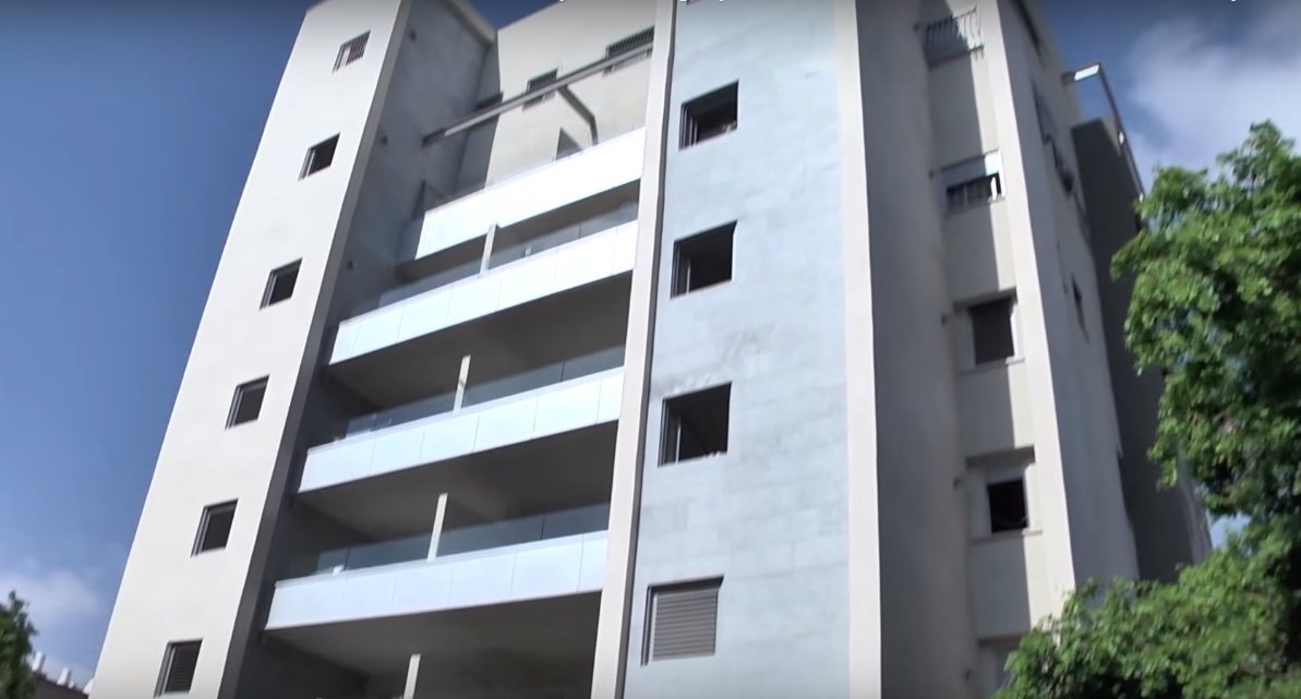 Un edificio de apartamentos en proceso de fortalecimiento. Se pueden ver nuevas habitaciones a prueba de bombas a la derecha e izquierda de los balcones. (Captura de pantalla de YouTube)