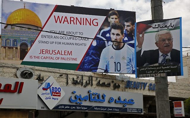 Este 5 de junio de 2018, la imagen muestra un cartel erigido en la ciudad cisjordana de Hebrón llamando a boicotear a la estrella de fútbol Lionel Messi (l) junto a un retrato del presidente de la Autoridad Palestina Mahmoud Abbas. (AFP / Hazem Bader)