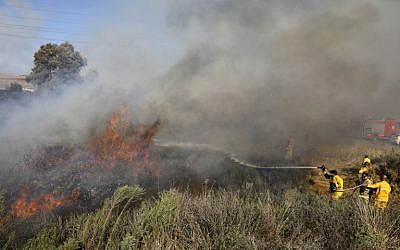 Los bomberos extinguen un incendio cerca de la ciudad sureña de Sderot causado por un globo incendiario lanzado desde la Franja de Gaza el 31 de julio de 2018. (AFP Photo / Menahem Kahana)