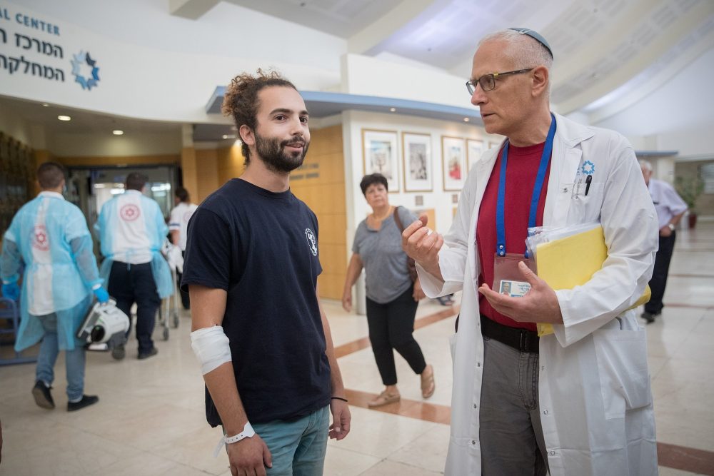 El Dr. David Raveh-Brawer habla con Yuval Miskin (L), que estaba infectado con la leptospirosis en los Altos del Golán, en el Centro Médico Sha'arei Tzedek en Jerusalén el 13 de agosto de 2018. (Yonatan Sindel / Flash90)