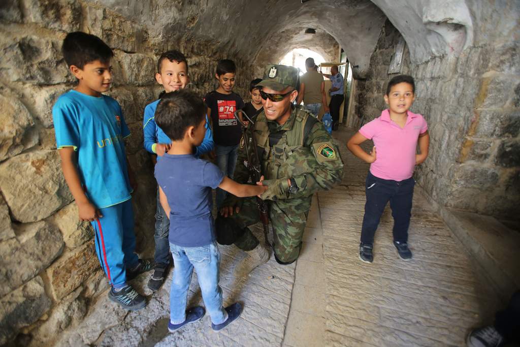 Miembro de las fuerzas de seguridad de la Autoridad Palestina interactuando con un niño en la ciudad vieja de Hebrón (Crédito: Wafa)