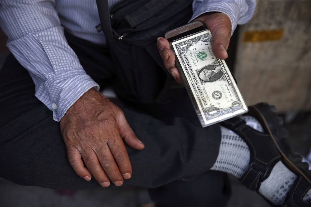 Un intercambiador de dinero callejero iraní sostiene un billete de banco estadounidense en el centro de Teherán, Irán, el 30 de julio de 2018 (AP Photo / Vahid Salemi)