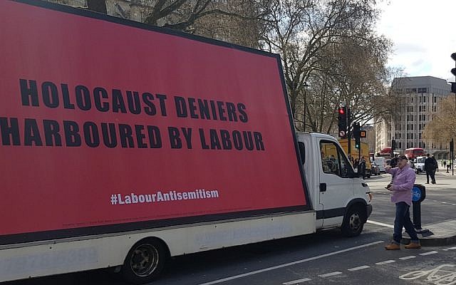 Keith Walker involucra al conductor de una furgoneta que transporta una cartelera sobre el antisemitismo en el Partido Laborista en la Plaza del Parlamento de Londres, el 17 de abril de 2018. (Cnaan Liphshiz / JTA)