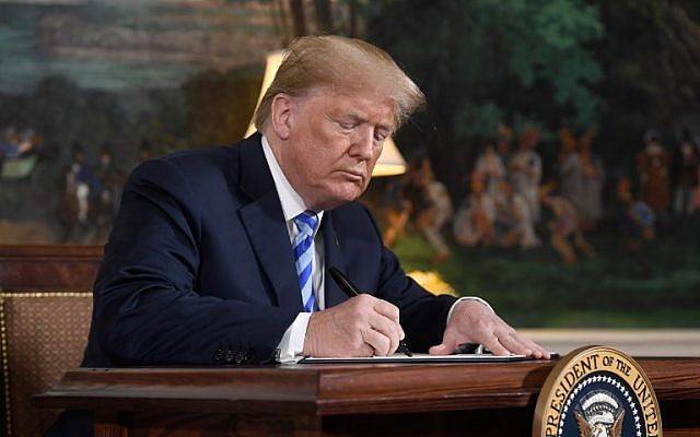El presidente estadounidense Donald Trump firma un documento que restablece las sanciones contra Irán después de anunciar la retirada de Estados Unidos del acuerdo nuclear iraní, en la sala de recepción diplomática en la Casa Blanca en Washington, DC, el 8 de mayo de 2018. (AFP / Saul Loeb)