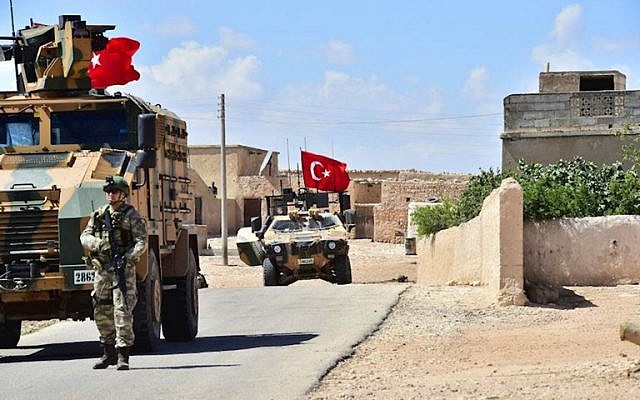 Una foto impresa publicada por el ejército turco muestra soldados turcos acompañados por vehículos blindados que patrullan entre la ciudad de Manbij en el norte de Siria y un área que controla después de una incursión militar de 2016-2017 el 18 de junio de 2018. (Fuerzas Armadas de Turquía / AFP)