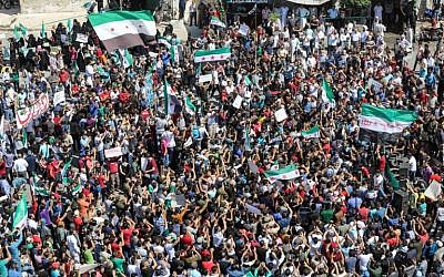 Los sirios de la ciudad norteña de Idlib, controlada por los rebeldes, y sus pueblos de alrededor agitan banderas de la oposición y corean consignas mientras se reúnen para una manifestación antigubernamental en Idlib el 14 de septiembre de 2018. (AFP Photo / Omar Haj Kadour)