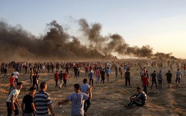 Los palestinos se reúnen durante una manifestación a lo largo de la valla fronteriza israelí al este de la ciudad de Gaza el 21 de septiembre de 2018, mientras las columnas de humo se elevan por la quema de neumáticos en el fondo. (AFP / Said Khatib)