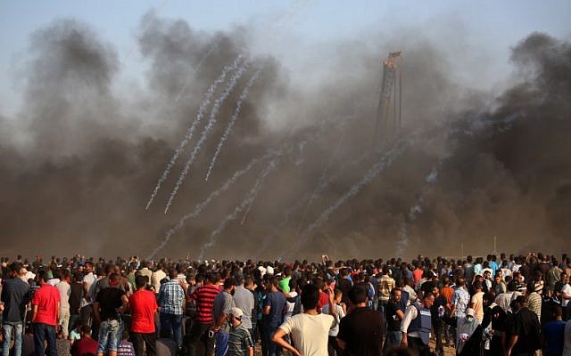 Los palestinos reaccionan cuando los gases lacrimógenos lanzados por las fuerzas israelíes caen durante los ataques de Hamás a lo largo de la valla fronteriza israelí, al este de la ciudad de Gaza el 28 de septiembre de 2018. (AFP PHOTO / SAID KHATIB)
