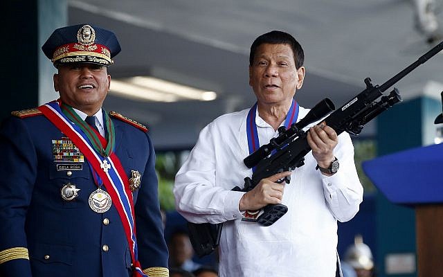 El presidente filipino, Rodrigo Duterte, bromea con los fotógrafos mientras sostiene un rifle Galil de fabricación israelí que le fue presentado por el ex director general de la Policía Nacional de Filipinas, Ronald "Bato" Dela Rosa, en la ceremonia de entrega de mando en el Campamento Crame en la ciudad de Quezon, al noreste de Manila, el 19 de abril de 2018. (Bullit Marquez / AP)