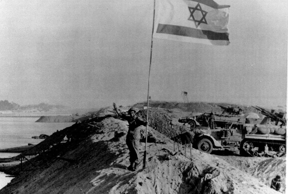 En esta foto de archivo del 30 de octubre de 1973, una gran bandera israelí revolotea sobre la orilla este recapturada del Canal de Suez. Las fuerzas egipcias habían invadido el canal en los primeros días de la guerra de Yom Kippur. (Foto AP)