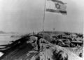 En esta foto de archivo del 30 de octubre de 1973, una gran bandera israelí revolotea sobre la orilla este recapturada del Canal de Suez. Las fuerzas egipcias habían invadido el canal en los primeros días de la guerra de Yom Kippur. (Foto AP)