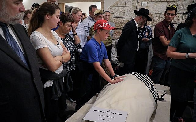 El hijo de Ari Fuld coloca sus manos sobre el cuerpo de su padre en su funeral en Kfar Etzion el 17 de septiembre de 2018. (Gershon Elinson / FLASH90)