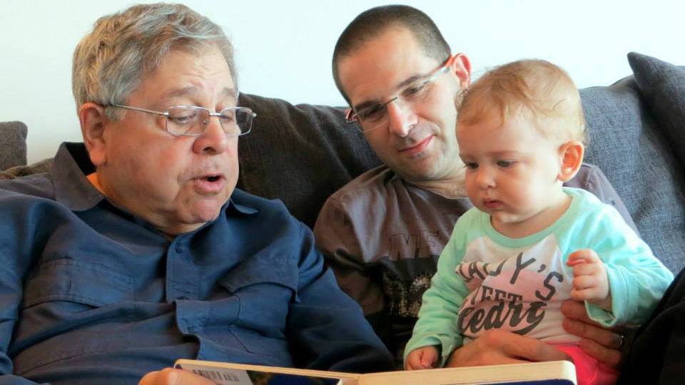Richard Lakin (izquierda) le lee un libro a su nieta, mientras su hijo Micah Avni observa. Enero de 2014. (Cortesía)