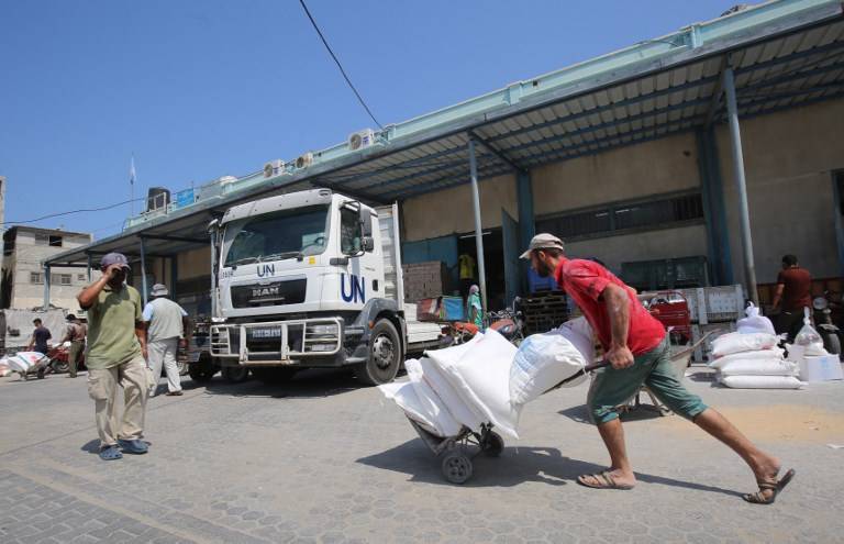 Un árabe transporta bolsas de harina afuera de un centro de distribución de ayuda administrado por la Agencia de Socorro y Obras de las Naciones Unidas (UNRWA), en Khan Younis en el sur de la Franja de Gaza, el 4 de septiembre de 2018. (Said Khatib / AFP)