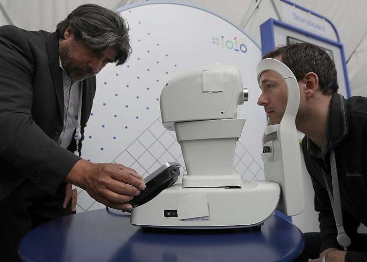 Jorge Cuadros, izquierda, ofrece una demostración de una cámara de retina robótica a un periodista en la conferencia Google I / O en Mountain View, California, el 8 de mayo de 2018 (AP Photo / Jeff Chiu)