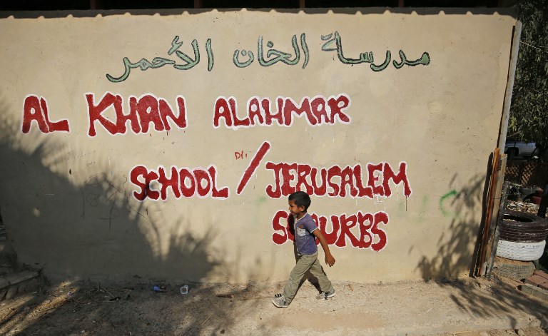 Un niño palestino pasa frente al muro de la escuela Khan al-Ahmar el primer día de clases en el pueblo beduino de Cisjordania el 16 de julio de 2018. (Abbas Momani / AFP)