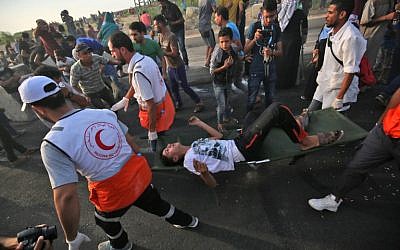 Los paramédicos llevan a un hombre herido mientras los palestinos se manifiestan en el cruce fronterizo de Erez con Israel en el norte de la Franja de Gaza el 3 de octubre de 2018. (AFP / Said Khatib)