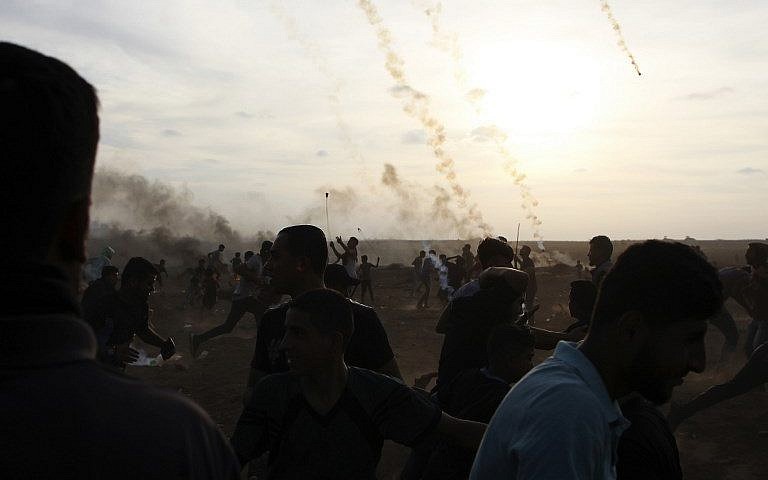 Los palestinos reaccionan cuando los botes de gas lacrimógeno disparados por las fuerzas israelíes caen durante ataques al este de la ciudad de Gaza, a lo largo de la frontera entre la Franja de Gaza e Israel, el 5 de octubre de 2018. (AFP Photo / Said Khatib)