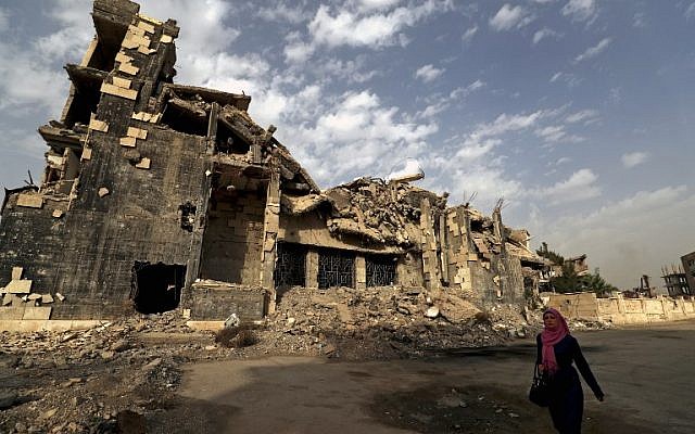 Una mujer pasa junto a un edificio dañado en la ciudad siria de Raqqa el 13 de octubre de 2018. (Delil Souleiman / AFP)