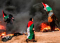 mujeres palestinas portan y visten banderas palestinas mientras se encuentran en medio del humo de los neumáticos quemados durante los ataques cerca de la frontera con Israel al este de la ciudad de Gaza el 26 de octubre de 2018 AFP