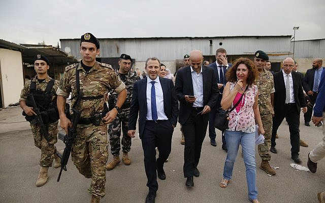 Soldados libaneses custodian mientras el Ministro de Relaciones Exteriores libanés Gebran Bassil, centro, recorre un sitio junto a un club de fútbol, ​​con diplomáticos y periodistas, uno de varios lugares que visitaron cerca del aeropuerto internacional de Beirut, en Beirut, Líbano, 1 de octubre de 2018. (Foto AP) / Hassan Ammar)