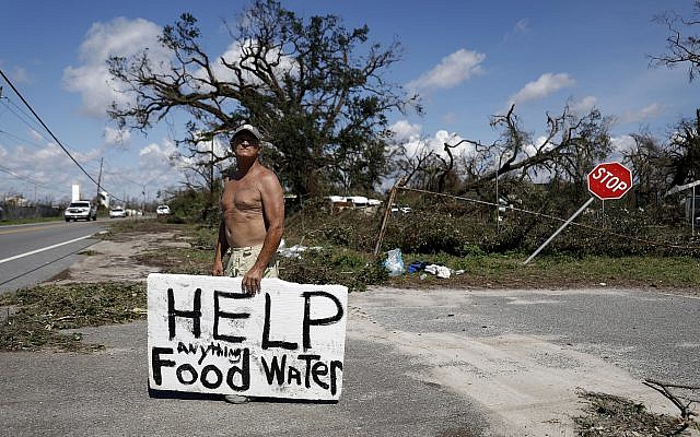 Michael Williams, de 70 años, busca ayuda de conductores que pasan por comida y agua, ya que los árboles caídos le impiden salir de su casa dañada tras el huracán Michael con su familia en Springfield, Florida, el jueves 11 de octubre de 2018. (Foto AP / David Goldman)