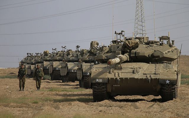 Soldados israelíes pasan frente a tanques en un punto de reunión cerca de la frontera de Gaza con Israel, 19 de octubre de 2018. (Foto AP / Ariel Schalit)