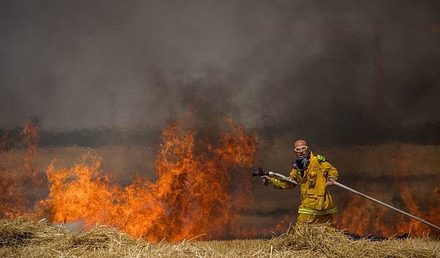 Bomberos israelíes apagan un incendio en un campo de trigo causado por cometas voladas por terroristas palestinos, cerca de la frontera con la Franja de Gaza, 30 de mayo de 2018. (Yonatan Sindel / Flash90)