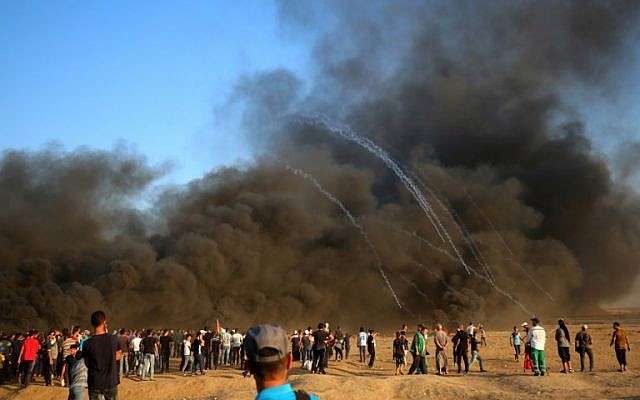 El 12 de octubre de 2018, islamistas palestinos se reúnen en el humo que se alza al quemar llantas entre Gaza e Israel, al este de la ciudad de Gaza. (Foto de SAID KHATIB / AFP)