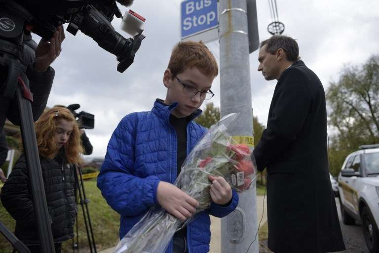 Un niño lleva a flores a un memorial el 28 de octubre de 2018, cerca de la sinagoga Árbol de la Vida, luego de que un tiroteo dejó 11 personas muertas en el vecindario de Squirrel Hill en Pittsburgh el 27 de octubre de 2018 (Dustin Franz / AFP)