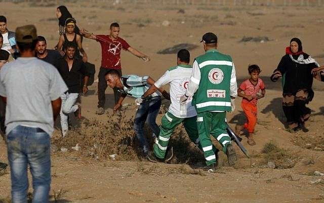 Los paramédicos palestinos ayudan a un violento islamista en la frontera entre Israel y Gaza, al este de la ciudad de Gaza, el 12 de octubre de 2018. (Said Khatib / AFP)