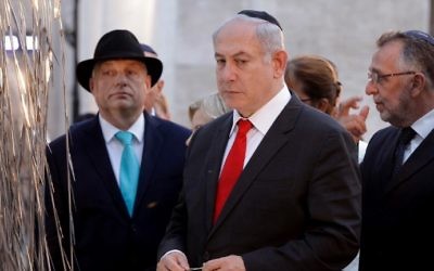 El primer ministro Benjamin Netanyahu (C) y el primer ministro húngaro, Viktor Orban, leyeron los nombres de las víctimas húngaras del Holocausto en las hojas de metal del 'árbol memorial de Emanuel' en el jardín conmemorativo Raoul Wallenberg de la sinagoga de Budapest en Budapest el 19 de julio de 2017. ( PETER KOHALMI / AFP)