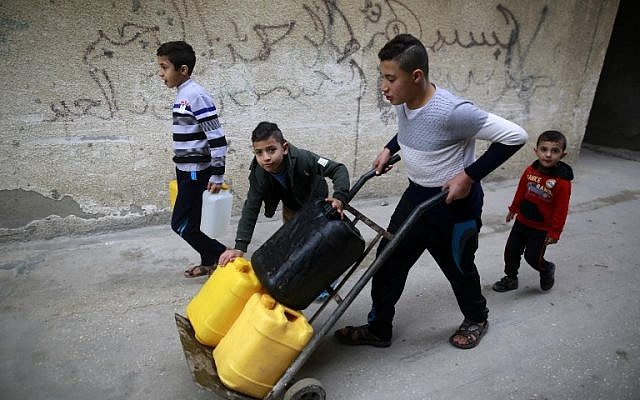 Los niños palestinos cargan botellas de agua en el campamento de refugiados de al-Shati en la ciudad de Gaza el 4 de enero de 2018. (AFP PHOTO / MOHAMMED ABED)