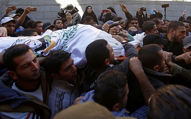 Los afligidos cantan consignas islamistas mientras portaban el cuerpo del comandante de Hamás, Nour Barakeh, quien fue asesinado durante una incursión israelí, durante su funeral, en la casa de su familia en Khan Younis, sur de la Franja de Gaza, 12 de noviembre de 2018. (Foto AP / Adel Hana)