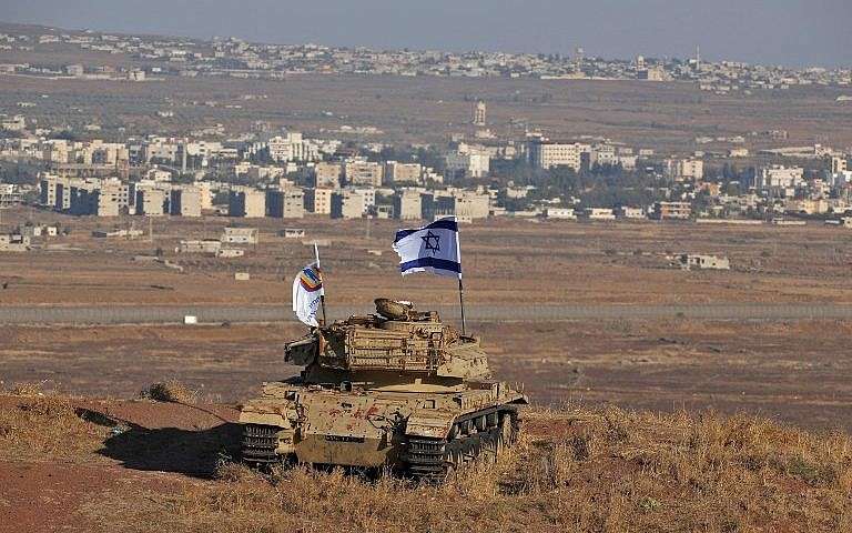 Una bandera israelí ondea sobre los restos de un tanque en una colina en los Altos del Golán que domina la frontera con Siria el 18 de octubre de 2017. (Foto de AFP / Jalaa Marey)