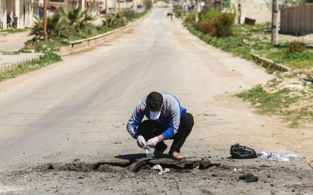 Un hombre sirio recolecta muestras del sitio de un presunto ataque con gas tóxico en Khan Sheikhoun, en la provincia de Idlib, noroeste de Siria, el 5 de abril de 2017. (AFP / Omar Haj Kadour)