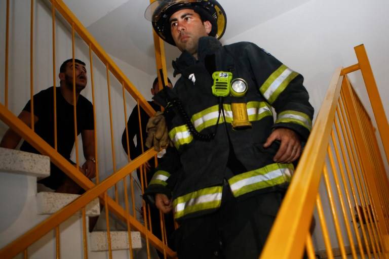 Un bombero israelí evacua un edificio tras un cohete lanzado desde la Franja de Gaza, en la ciudad de Ashkelon, al sur de Israel, el 12 de noviembre de 2018. (GIL COHEN-MAGEN / AFP)