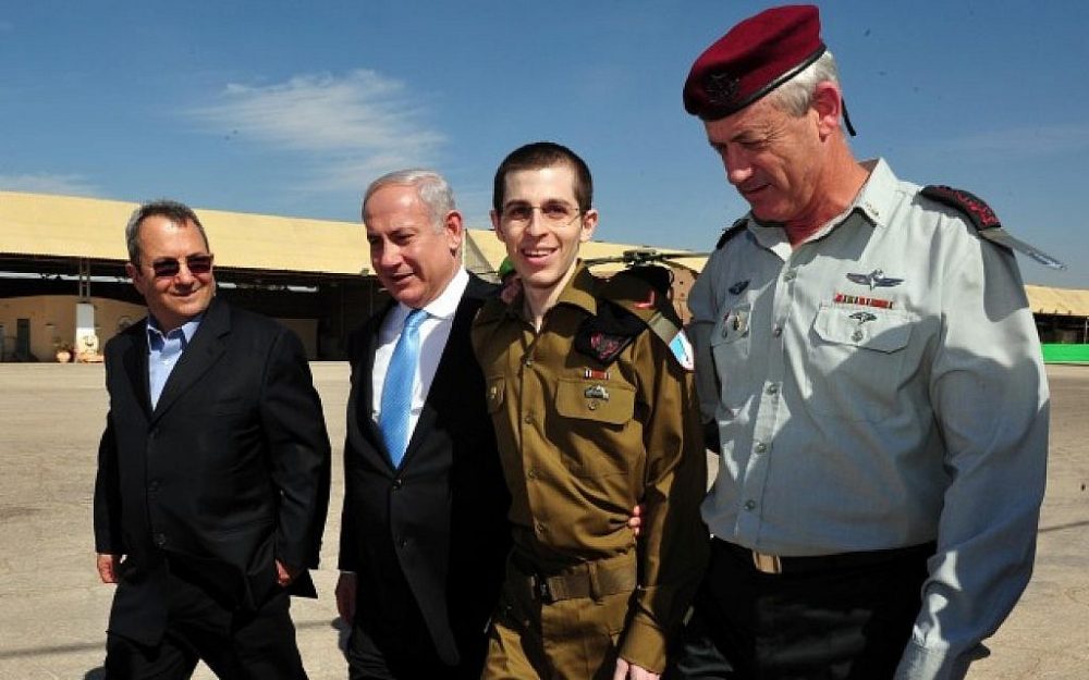 El soldado israelí liberado Gilad Shalit (segundo a la derecha), camina con el primer ministro Benjamin Netanyahu (segundo a la izquierda), el entonces ministro de defensa Ehud Barak (izquierda) y el ex jefe de personal, el teniente general Benny Gantz (derecha), en el Tel. Nof base aérea en el sur de Israel, 18 de octubre de 2011. (Ariel Hermoni / Ministerio de Defensa / Flash90)