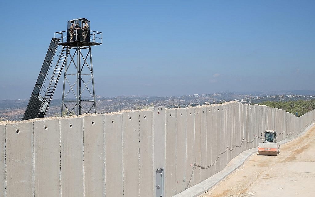 Un vehículo de construcción israelí conduce por un muro de hormigón que se está construyendo a lo largo de la 'Línea Azul' que separa a Israel y el Líbano, mientras miembros de las Fuerzas Armadas Libanesas observan desde una torre de vigilancia, cerca de la ciudad israelí de Rosh Hanikra el 5 de septiembre de 2018. (Judah Ari Gross / tiempos de Israel)