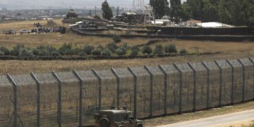 Una fotografía tomada el 4 de julio de 2018 desde los Altos del Golán muestra a sirios desplazados de la provincia de Daraa realizando una protesta (parte superior L) que reclama protección internacional, en la aldea siria de al-Rafid, cerca de la frontera con Israel. (AFP / Jalaa Marey)