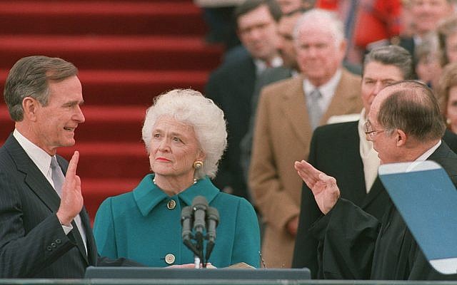 En esta foto de archivo del 20 de enero de 1989, el presidente George HW Bush levanta su mano derecha cuando toma posesión de su cargo como presidente número 41 de los Estados Unidos por el presidente William Rehnquist, frente al frente oeste del Capitolio, como primera dama Barbara Bush sostiene la biblia para su esposo (Foto AP / Bob Daugherty, Archivo)