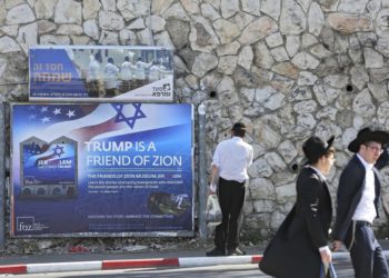 Los judíos ultraortodoxos pasan por un cartel que recibe al presidente de los Estados Unidos, Donald Trump, antes de su visita, en Jerusalén, el 19 de mayo de 2017. (Foto AP / Oded Balilty)