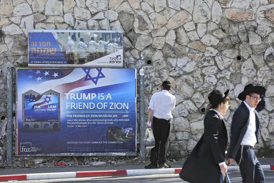 Los judíos ultraortodoxos pasan por un cartel que recibe al presidente de los Estados Unidos, Donald Trump, antes de su visita, en Jerusalén, el 19 de mayo de 2017. (Foto AP / Oded Balilty)
