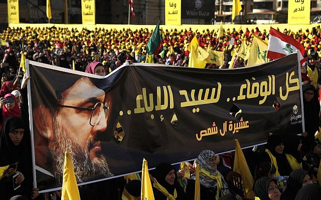 En esta foto del 13 de abril de 2018, los partidarios del líder de Hezbolá, Sayyed Hassan Nasrallah, sostienen una pancarta con su retrato y palabras en árabe que dicen: 'Toda la lealtad al hombre de la nobleza'. (AP / Hussein Malla)