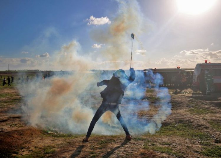 Un palestino usa una honda para lanzar gases lacrimógenos contra las fuerzas israelíes durante una manifestación en la cerca israelí al este de la ciudad de Gaza el 18 de enero de 2019. (Dijo KHATIB / AFP)