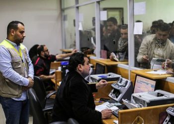 Los trabajadores de correos ayudan a los palestinos que llegaron a la oficina central de correos en la ciudad de Gaza el 26 de enero de 2019, para recibir ayuda financiera del gobierno de Qatar que se otorga a familias empobrecidas. (Mahmud Hams / AFP)